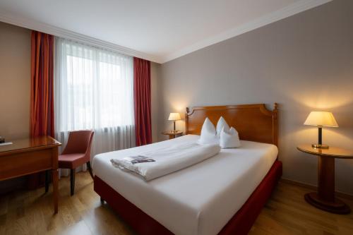 a hotel room with a bed and a desk and a window at Hotel Goldene Sonne in Landshut