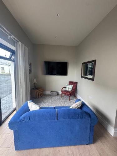 a living room with a blue couch and a tv at Milton on The Moyle Apartments in Buncrana