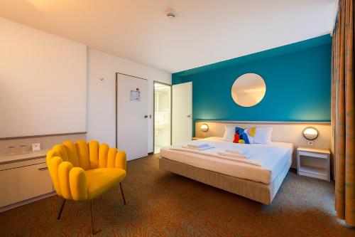 a hotel room with a bed and a yellow chair at Hessenland Hotel Kassel Innenstadt by Stay Awesome in Kassel