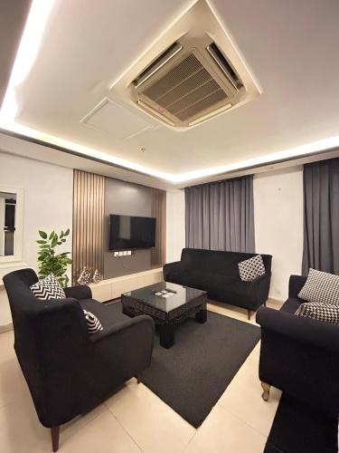 a living room with two couches and a tv at Luxury Apartments at Goldcrest Mall and Residency DHA Phase 4 by Nirvana Nests in Lahore