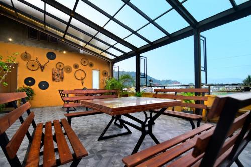 a patio with wooden tables and benches and windows at Green View Peak Restaurant in Gampola