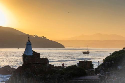 a lighthouse on the shore of a body of water with a boat at Casa Dal Mare in Knysna