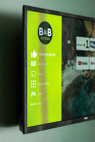 a television with a green screen on a wall at B&B HOTEL La Réunion Aéroport in Sainte-Marie