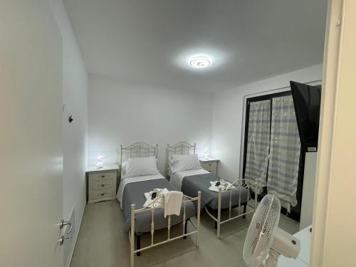 a bedroom with two beds and a tv and a window at CASA NINA affittacamere in Camerino