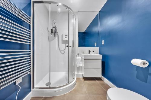 a blue bathroom with a shower and a toilet at The Liverpool Street Boutique in London
