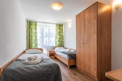 a bedroom with two beds and a cabinet at DIUNA Łeba in Łeba