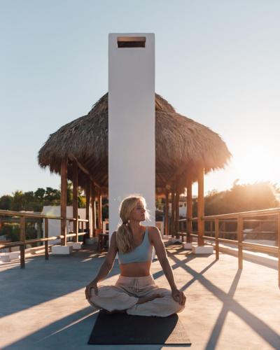 a woman is sitting in a yoga pose on the floor at Casa Ohma La Punta in Brisas de Zicatela