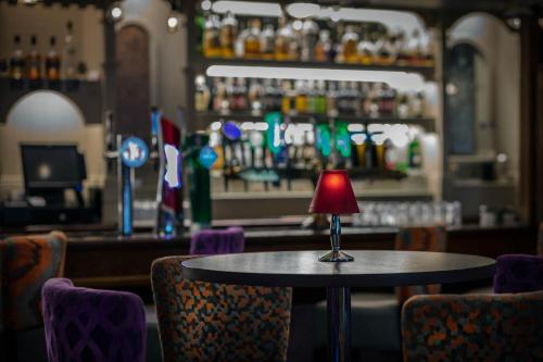 a red lamp sitting on a table in a bar at Woodford Dolmen Hotel Carlow in Carlow