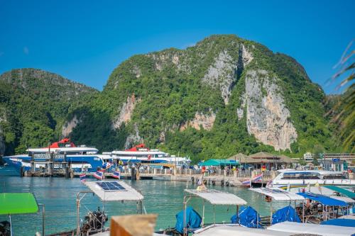 a bunch of boats docked at a dock with a mountain at Phi Phi at Pier in Phi Phi Don