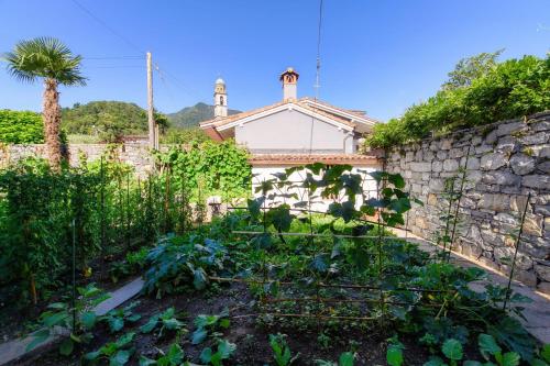 a garden with a stone wall and a building at Al Capriccio Apartment by Quokka 360 - 5 minutes from the centre of Ascona in Losone
