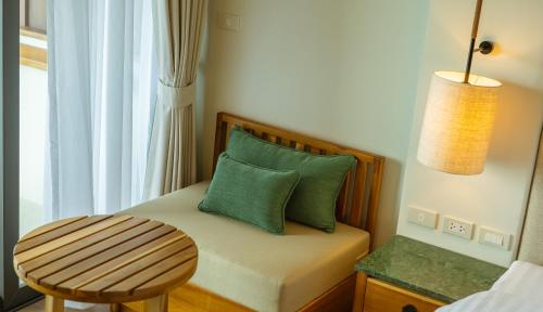 a small bed with a green pillow and a stool at Phi Phi at Pier in Phi Phi Don