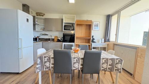 a kitchen with a table with chairs and a refrigerator at Appartement avec forêt et vue, 2 chambres in Égat