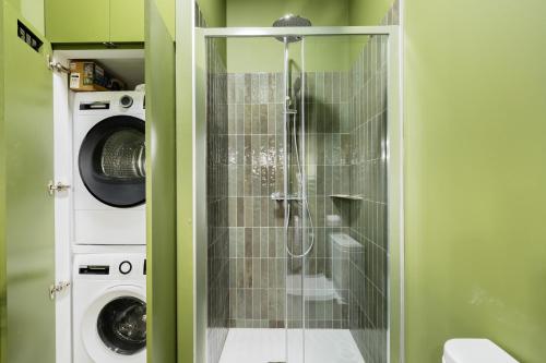 La salle de bains est pourvue d'une douche en verre et d'un lave-linge. dans l'établissement Appartement 2ch Tout Neuf à Deux Pas du Vieux Port, à La Rochelle