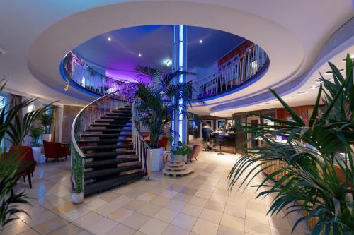 a lobby with stairs and plants in a building at Hessenland Hotel Kassel Innenstadt by Stay Awesome in Kassel