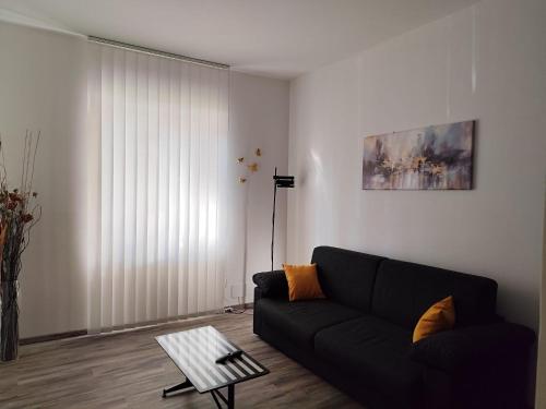 a living room with a black couch and a table at Biella Living in Biella