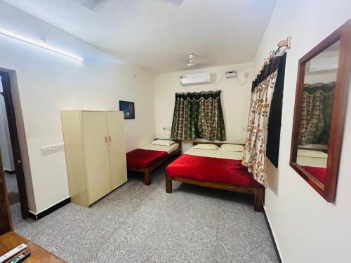 a small room with two beds and a refrigerator at Lotus Garden Guest House in Auroville