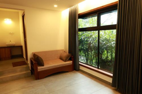 a room with a chair and a large window at Swiss Holidays in Pinangode