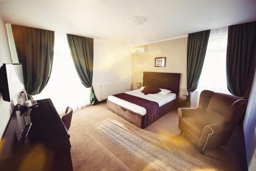 a hotel room with a bed and a chair at Coquette VILLA Mamaia Nord in Mamaia Sat/Năvodari