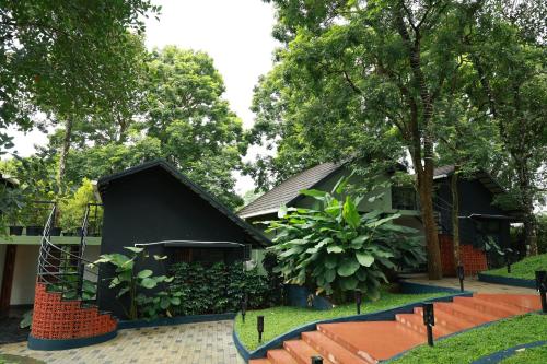 a house with a black building and trees at Swiss Holidays in Pinangode