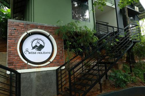 a sign on a brick wall with a staircase at Swiss Holidays in Pinangode