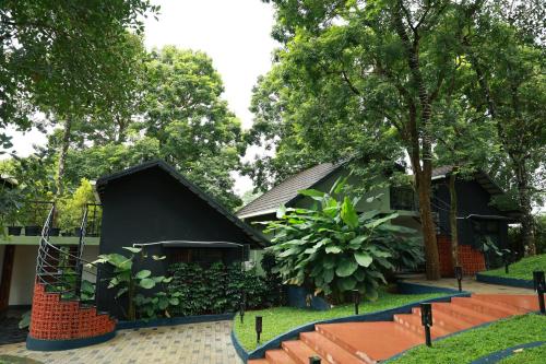 a house with a black roof and a tree at Swiss Holidays in Pinangode