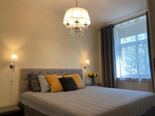 a bedroom with a bed with a chandelier and a window at Compass apartment in Tallinn