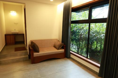a room with a chair and a large window at Swiss Holidays in Pinangode