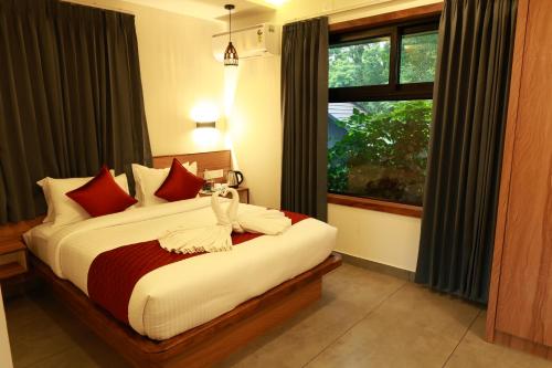 a bedroom with a bed with red pillows and a window at Swiss Holidays in Pinangode