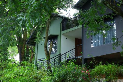 a green and white house with a tree at Swiss Holidays in Pinangode