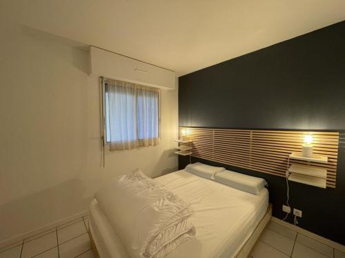 - une chambre avec un lit blanc et un mur noir dans l'établissement Agréable T2 avec piscine et animaux admis - FR-1-379-182, à Soustons