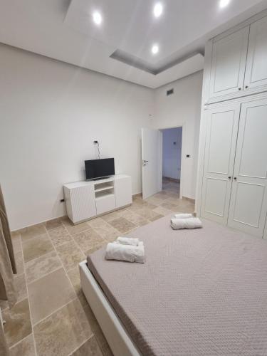a white room with a bed and a flat screen tv at Villa Zagara Pool e Sea in San Pietro in Bevagna