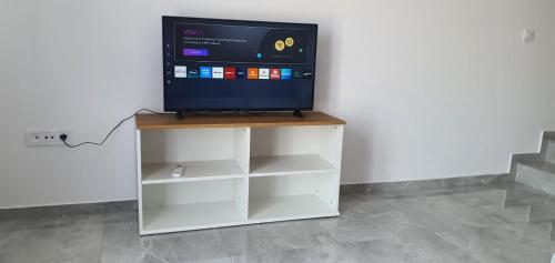 a flat screen tv sitting on top of a white cabinet at Heracles Guest house in Néa Péramos