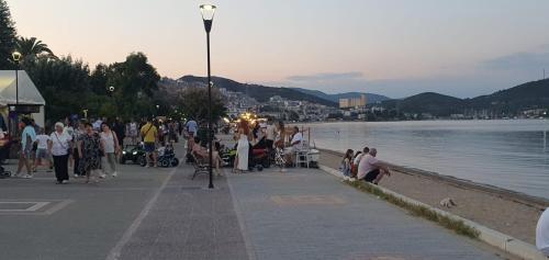 a group of people walking on a sidewalk next to the water at Heracles Guest house in Néa Péramos