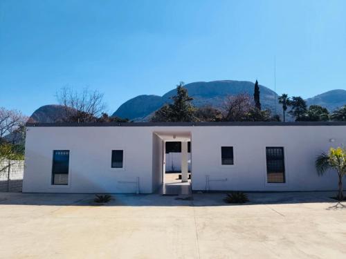 a white building with a door and mountains in the background at Mthiyane Dam View in Hartbeespoort