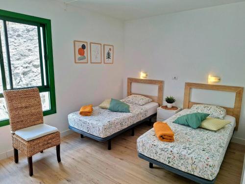 Una habitación con dos camas y una silla dentro. en Canaima 223 - Puerto Rico, en Puerto Rico de Gran Canaria