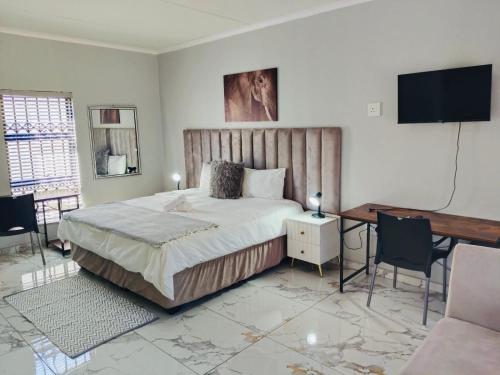 a bedroom with a bed and a desk and a television at Mthiyane Dam View in Hartbeespoort
