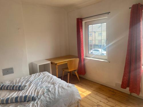 ニューマーケットにあるCharlies House Newmarket - 3 bedroomのベッドと机と窓のある寝室