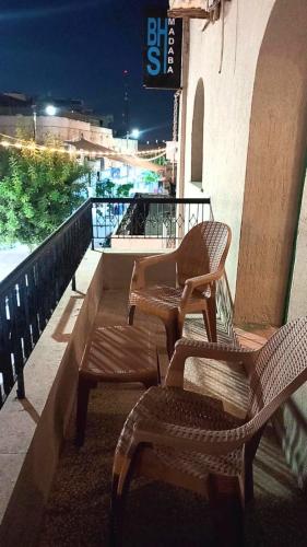a couple of chairs sitting on a balcony at night at Blue Stone H in Madaba