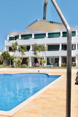 a hotel with a swimming pool in front of a building at Apartamento Malino in Sagres