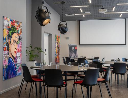 a conference room with tables and chairs and a projection screen at Radisson RED Hotel V&A Waterfront Cape Town in Cape Town