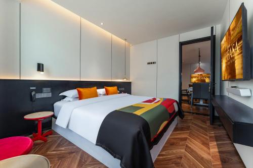 a bedroom with a large bed and a red chair at HeSu Hidden Art Hotel & Suites - Near Bell Tower & Ideal Location-Spacious rooms featuring King or Double Queen beds -Exclusive Two&Three-Bedroom Suites with Expansive Living Rooms for Group Gathering-Kitty Cuddles & Coffee Gift -Seamless Journey Planning in Xi'an