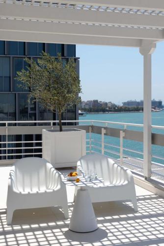 two white chairs and a table on a balcony at Port Tower Piraeus in Piraeus
