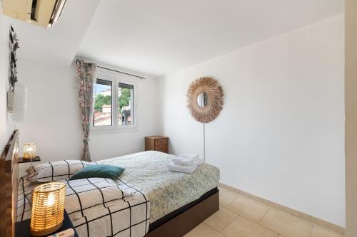 Un dormitorio blanco con una cama y un espejo. en Constance d'Azur - Climatisé vue mer, en Le Lavandou