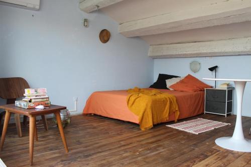- une chambre avec un lit avec une couverture orange et une table dans l'établissement Duplex climatisé avec terrasse, à Agde