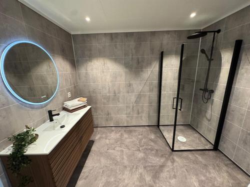 a bathroom with a shower and a sink and a mirror at Exclusive penthouse apartment near the sea and nature - Sæbøvik in Sæbøvik