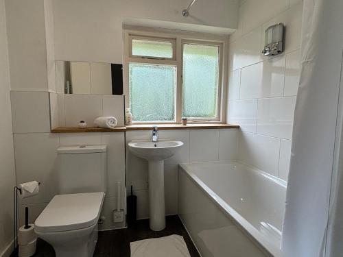 a bathroom with a sink and a toilet and a tub at 4 Bed House - Free Parking - 8 min LGW Airport in Crawley
