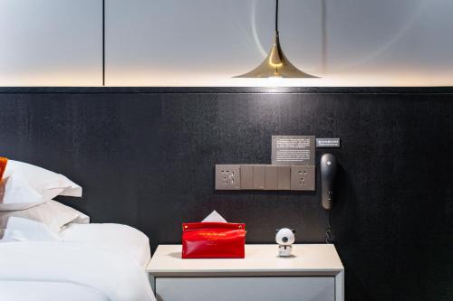 a hotel room with a bed and a red bag on a table at HeSu Hidden Art Hotel & Suites - Near Bell Tower & Ideal Location-Spacious rooms featuring King or Double Queen beds -Exclusive Two&Three-Bedroom Suites with Expansive Living Rooms for Group Gathering-Kitty Cuddles & Coffee Gift -Seamless Journey Planning in Xi'an