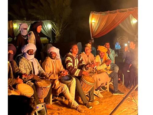 a group of people sitting in a group with drums at Moroccan Desert Camp in Merzouga
