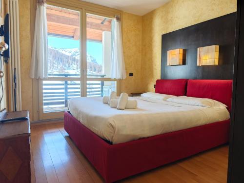 a red bed in a room with a large window at Hostdomus - Nube d'Argento in Sestriere