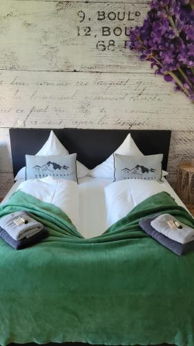 a large bed with a green blanket and white pillows at Ferienwohnung Lavendel in Oberstdorf